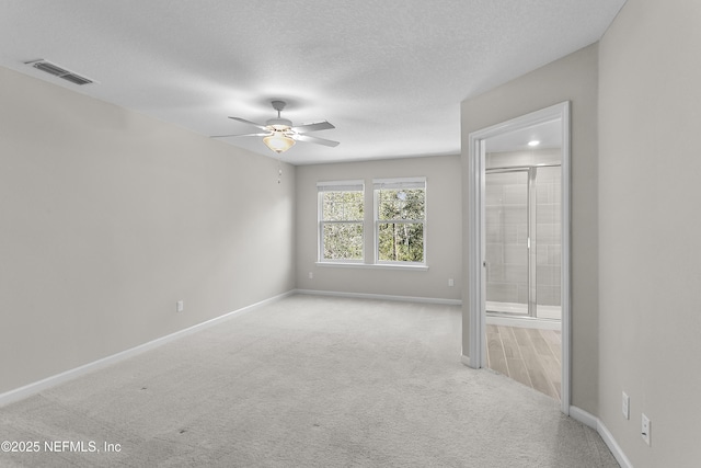 unfurnished bedroom featuring carpet, visible vents, a textured ceiling, and baseboards