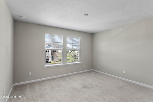 empty room featuring carpet, a textured ceiling, and baseboards