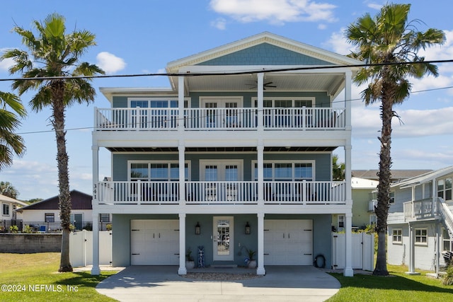 coastal home featuring a balcony, a garage, and a front lawn