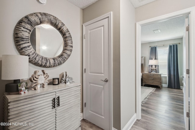 hallway with hardwood / wood-style floors and a textured ceiling