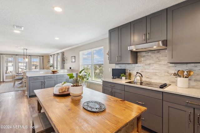 kitchen featuring tasteful backsplash, ornamental molding, dark hardwood / wood-style floors, pendant lighting, and gray cabinetry