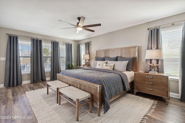 bedroom with a textured ceiling, dark hardwood / wood-style floors, and ceiling fan