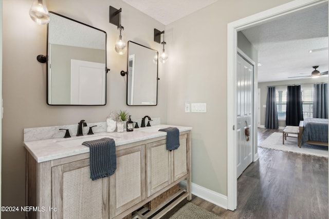 bathroom featuring vanity, ceiling fan, wood-type flooring, and a textured ceiling