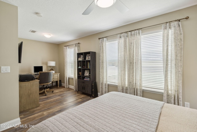 bedroom with a textured ceiling, dark hardwood / wood-style floors, and ceiling fan