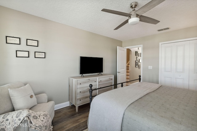 bedroom with dark hardwood / wood-style flooring, a textured ceiling, a closet, and ceiling fan