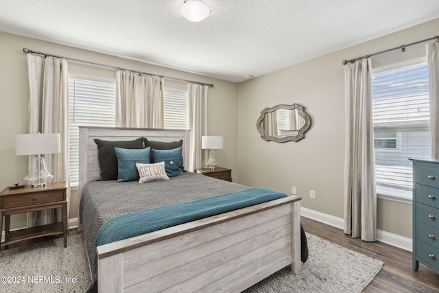 bedroom featuring multiple windows, a textured ceiling, and hardwood / wood-style flooring