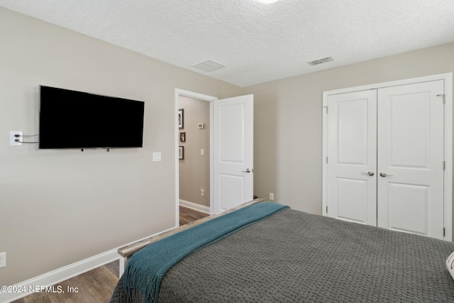 bedroom featuring a closet, a textured ceiling, and dark hardwood / wood-style flooring