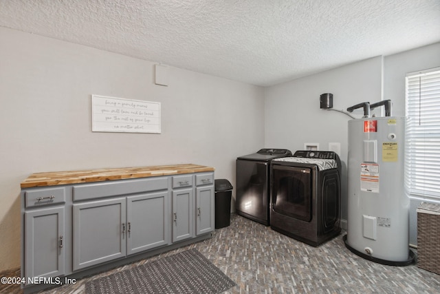 laundry room featuring a textured ceiling, electric water heater, independent washer and dryer, and cabinets