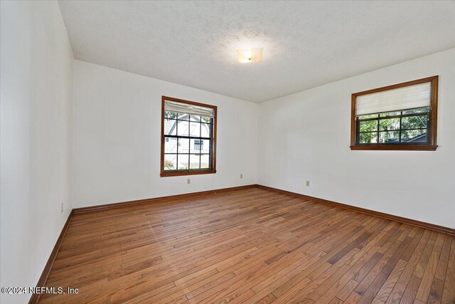 unfurnished room with light hardwood / wood-style flooring and a textured ceiling