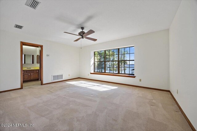 unfurnished bedroom with connected bathroom, ceiling fan, and light carpet