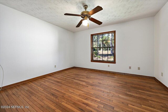 empty room with ceiling fan, dark wood-type flooring, and a textured ceiling