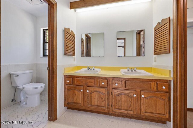 bathroom with tile patterned floors, vanity, toilet, and tile walls