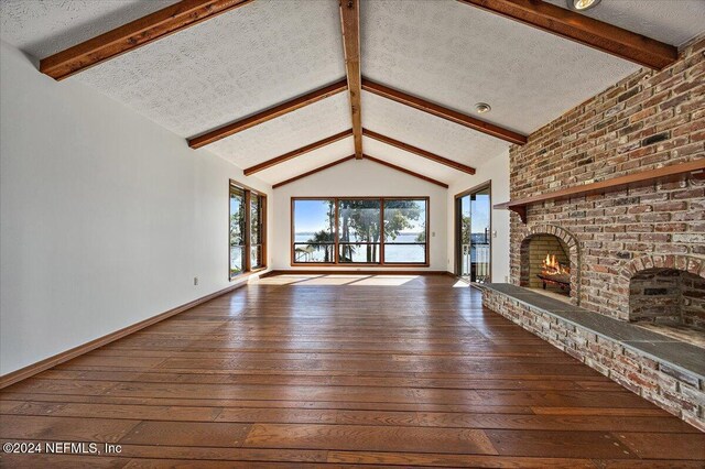 unfurnished living room featuring a fireplace, hardwood / wood-style floors, vaulted ceiling with beams, and a textured ceiling