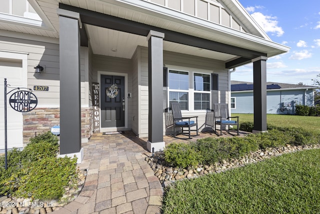 doorway to property with a porch and a lawn