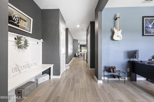 hallway with a textured ceiling and light hardwood / wood-style flooring