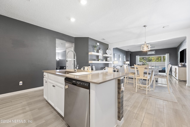 kitchen with stainless steel dishwasher, sink, white cabinets, and a center island with sink