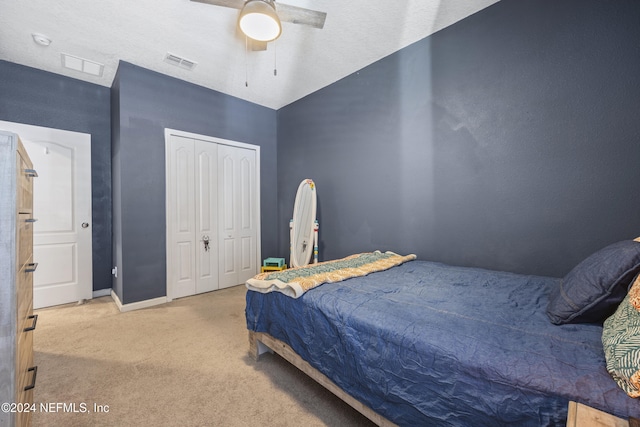 carpeted bedroom featuring a closet, ceiling fan, and a textured ceiling