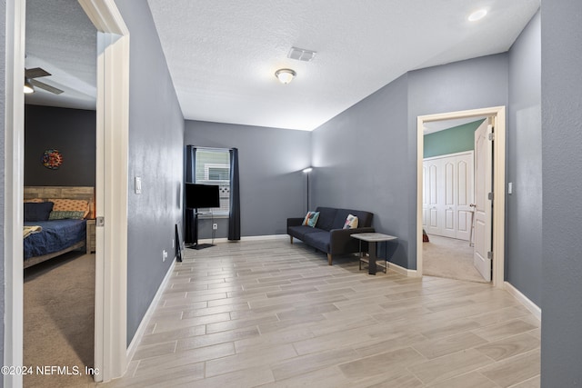 living area featuring a textured ceiling, light hardwood / wood-style floors, and ceiling fan