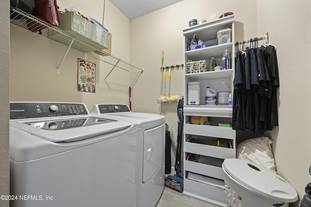 clothes washing area featuring a textured ceiling, light wood-type flooring, and separate washer and dryer