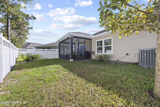 back of property with central air condition unit, a lawn, and a sunroom