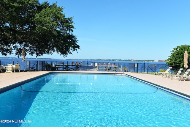 view of swimming pool featuring a water view and a patio area