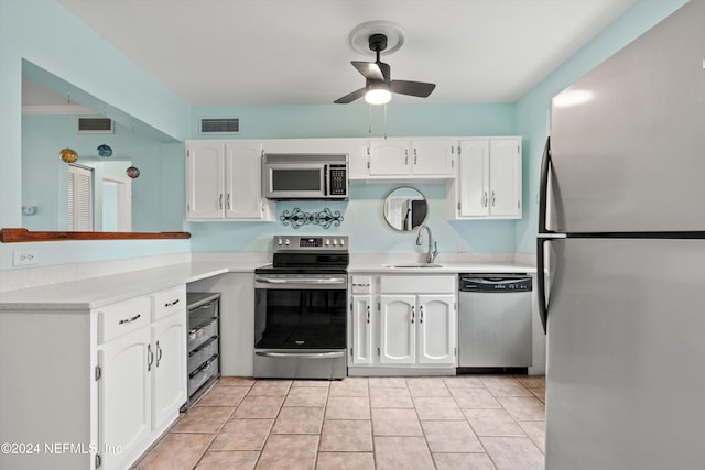 kitchen with stainless steel appliances, sink, light tile patterned floors, ornamental molding, and white cabinetry