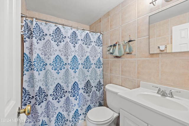 bathroom with vanity, toilet, and tile walls