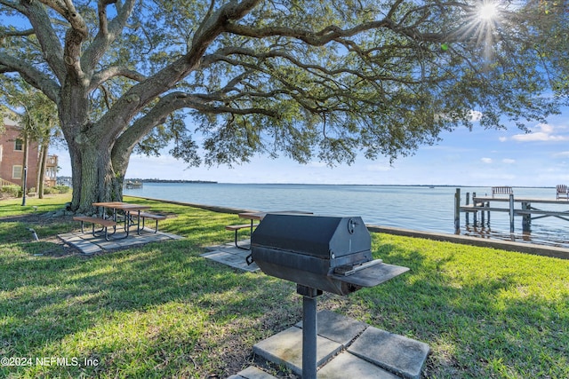 dock area featuring a water view, a lawn, and a patio area