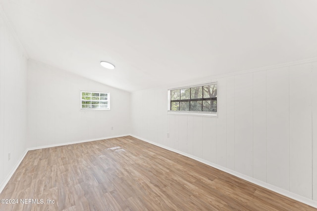 spare room with light hardwood / wood-style floors and vaulted ceiling