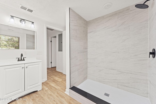 bathroom featuring vanity, a tile shower, a textured ceiling, and hardwood / wood-style floors