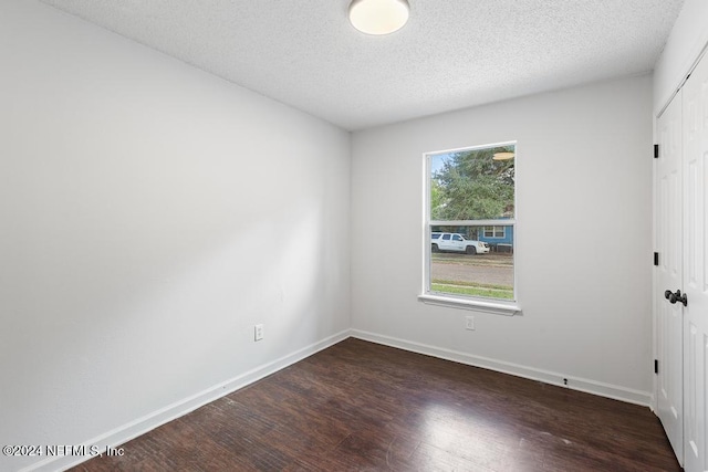 spare room featuring dark wood-type flooring and a textured ceiling