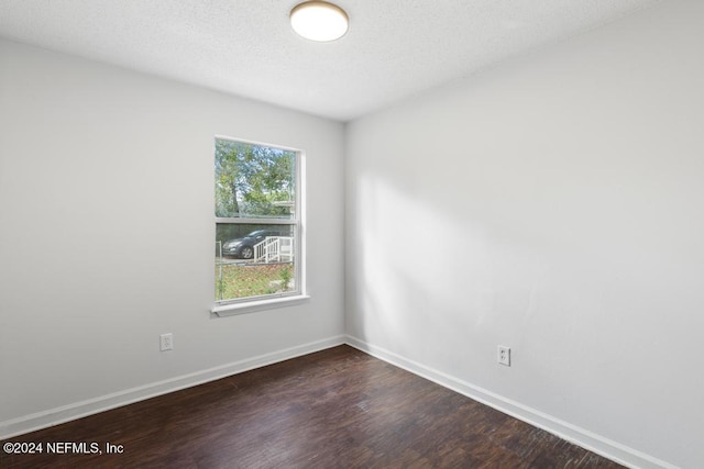 spare room featuring dark wood-type flooring and a textured ceiling