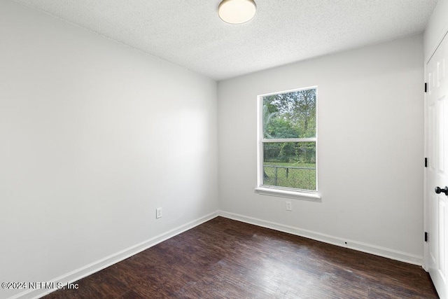 empty room with a textured ceiling and dark hardwood / wood-style flooring