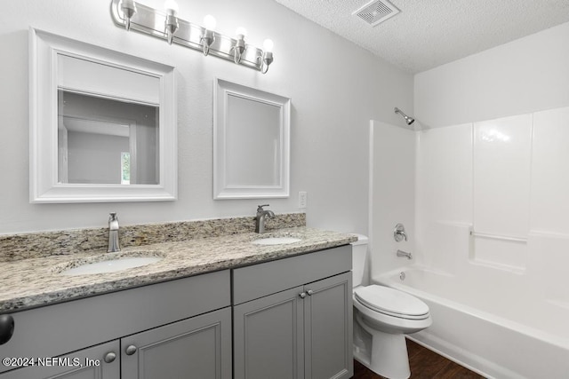 full bathroom with bathtub / shower combination, a textured ceiling, hardwood / wood-style floors, toilet, and vanity