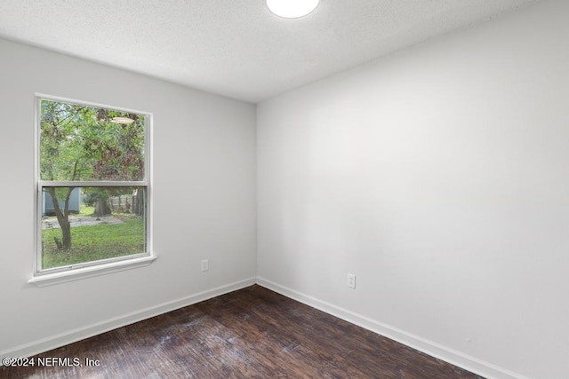 spare room with dark wood-type flooring and a textured ceiling