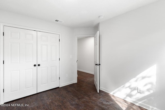 unfurnished bedroom with dark wood-type flooring and a closet