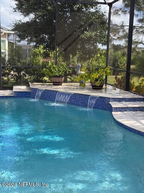 view of swimming pool featuring pool water feature and glass enclosure