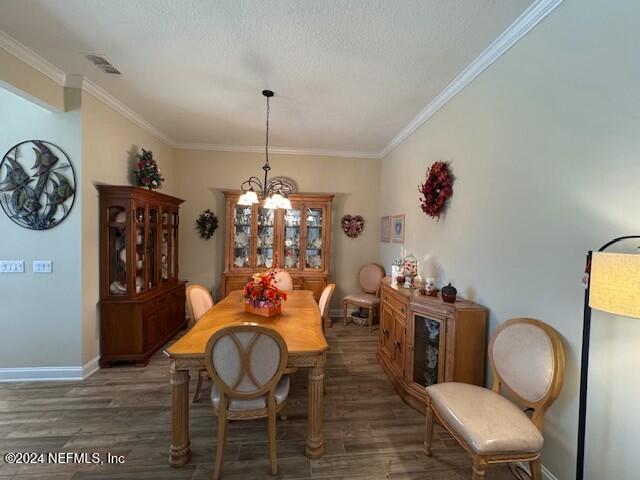 dining room featuring an inviting chandelier, a textured ceiling, dark hardwood / wood-style floors, and ornamental molding