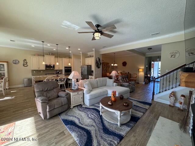 living room with wood-type flooring, a textured ceiling, ceiling fan, and crown molding