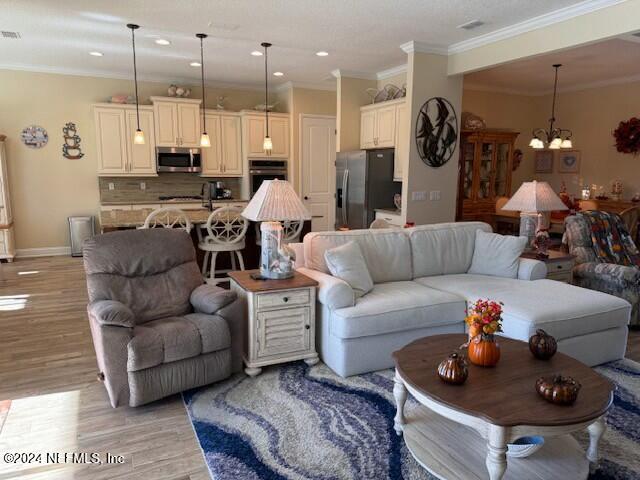 living room with a chandelier, light hardwood / wood-style flooring, and ornamental molding