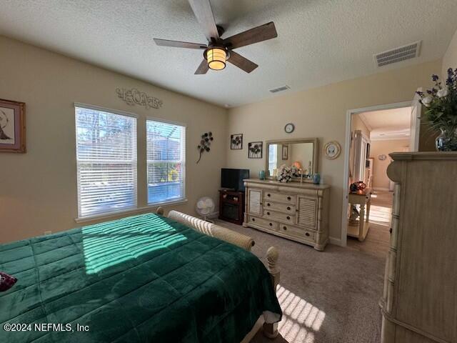 bedroom with ceiling fan, a textured ceiling, and carpet