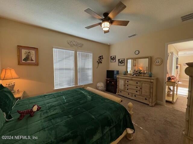 carpeted bedroom with ceiling fan and a textured ceiling