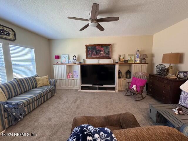 living room with ceiling fan, light colored carpet, and a textured ceiling