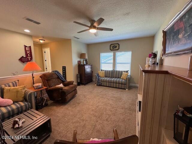 living room with ceiling fan, a textured ceiling, and carpet