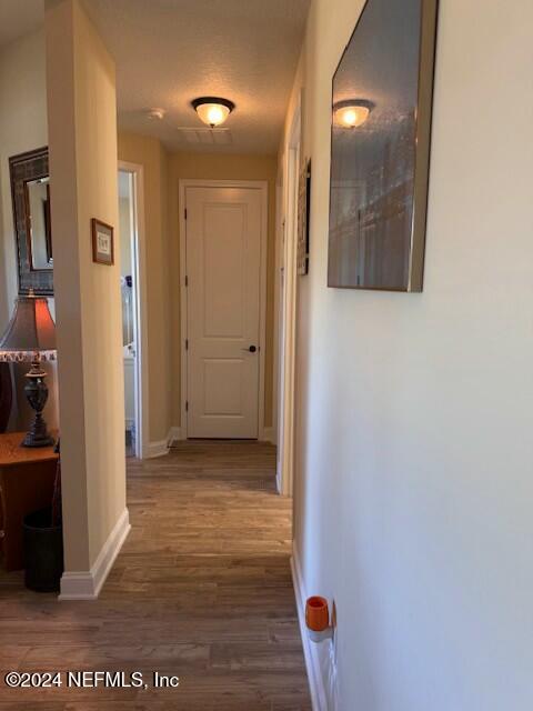 corridor featuring a textured ceiling and dark hardwood / wood-style flooring