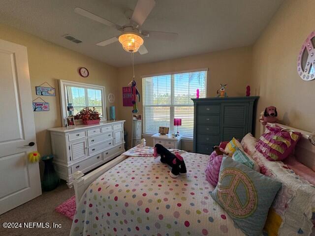 carpeted bedroom featuring ceiling fan and multiple windows