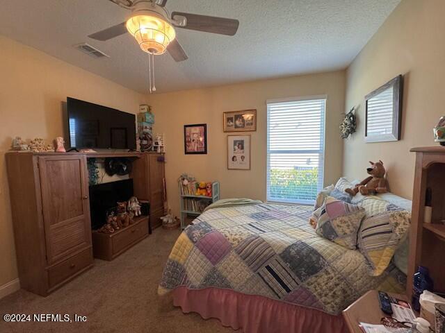 carpeted bedroom with ceiling fan and a textured ceiling