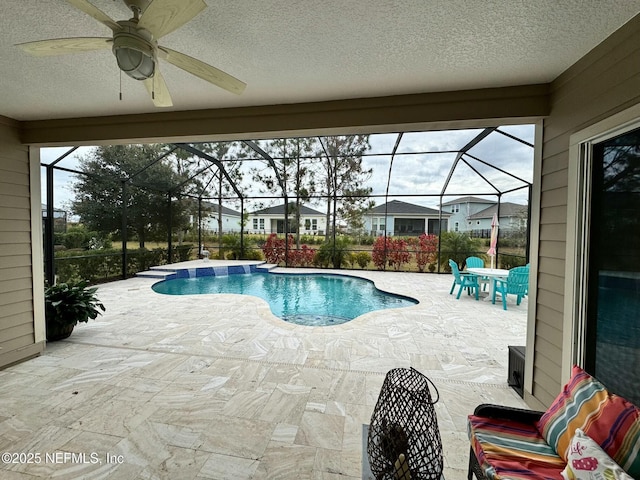 view of pool with glass enclosure, ceiling fan, and a patio area