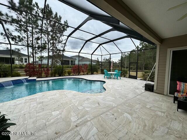 view of pool with glass enclosure, a patio, and pool water feature