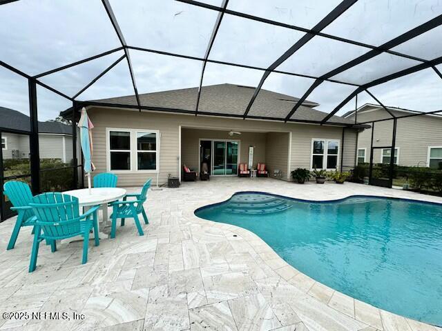 view of pool with glass enclosure and a patio